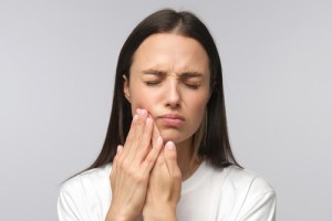 A young woman holding cheek in pain